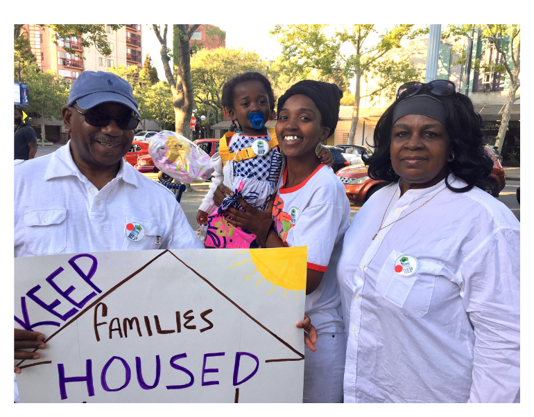 Family with 'Keep families housed' banner